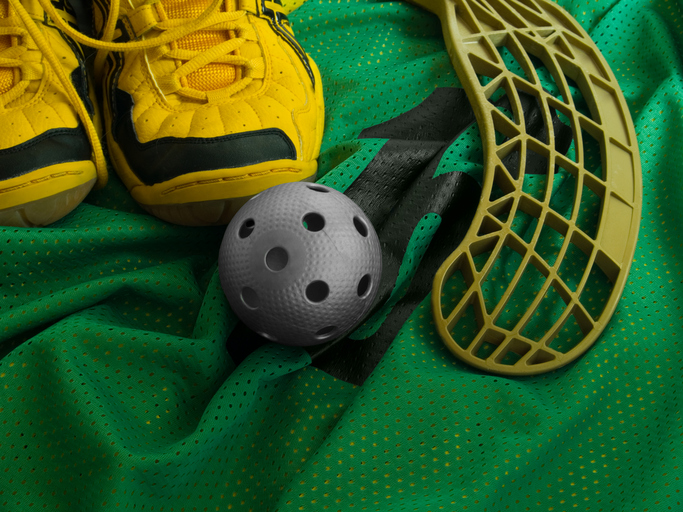 Floorball ball, stick, and shoes on a green jersey.